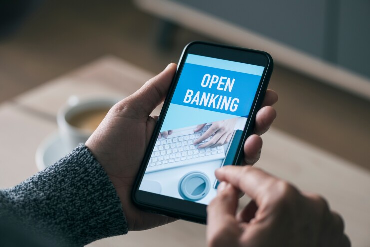 Open banking graphic on a phone that a person is holding